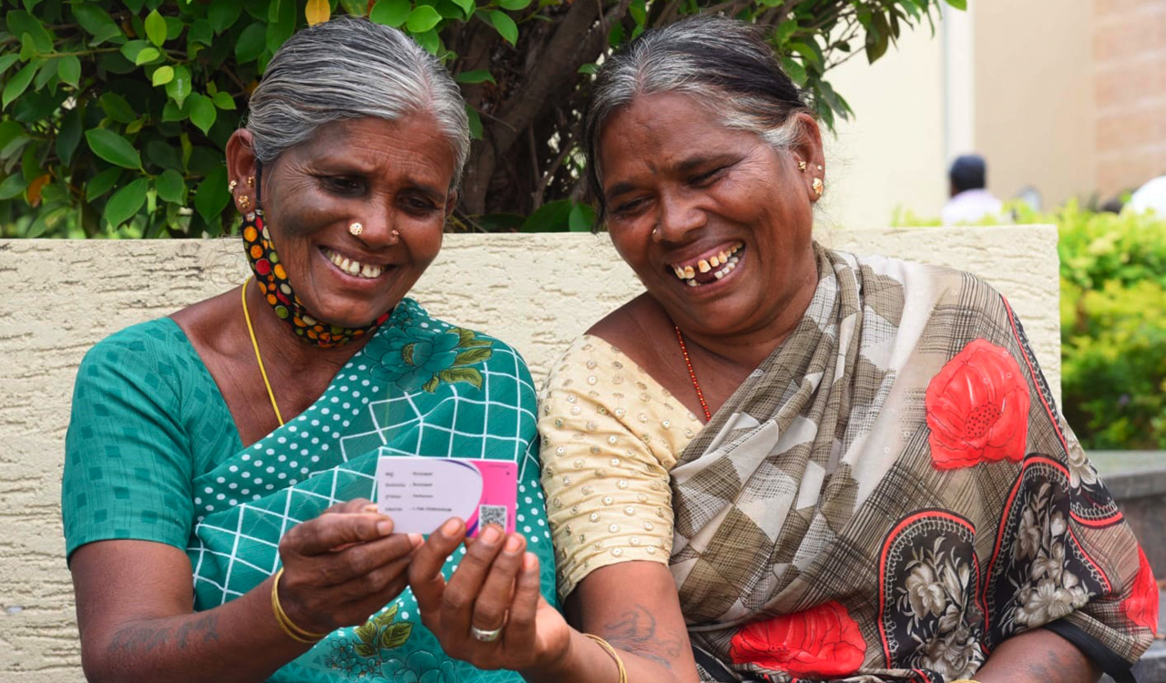 Two elderly women in Telangana holding their Aasara pension card