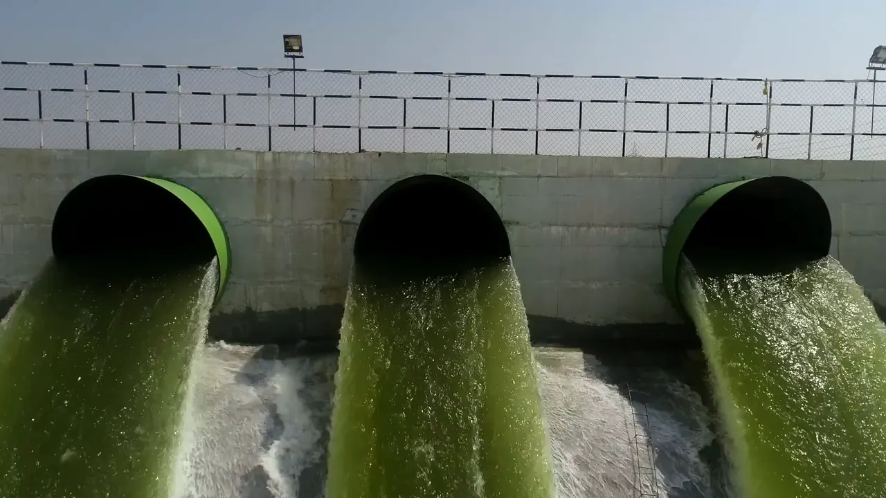 Three large delivery pipes discharging water under pressure into a channel